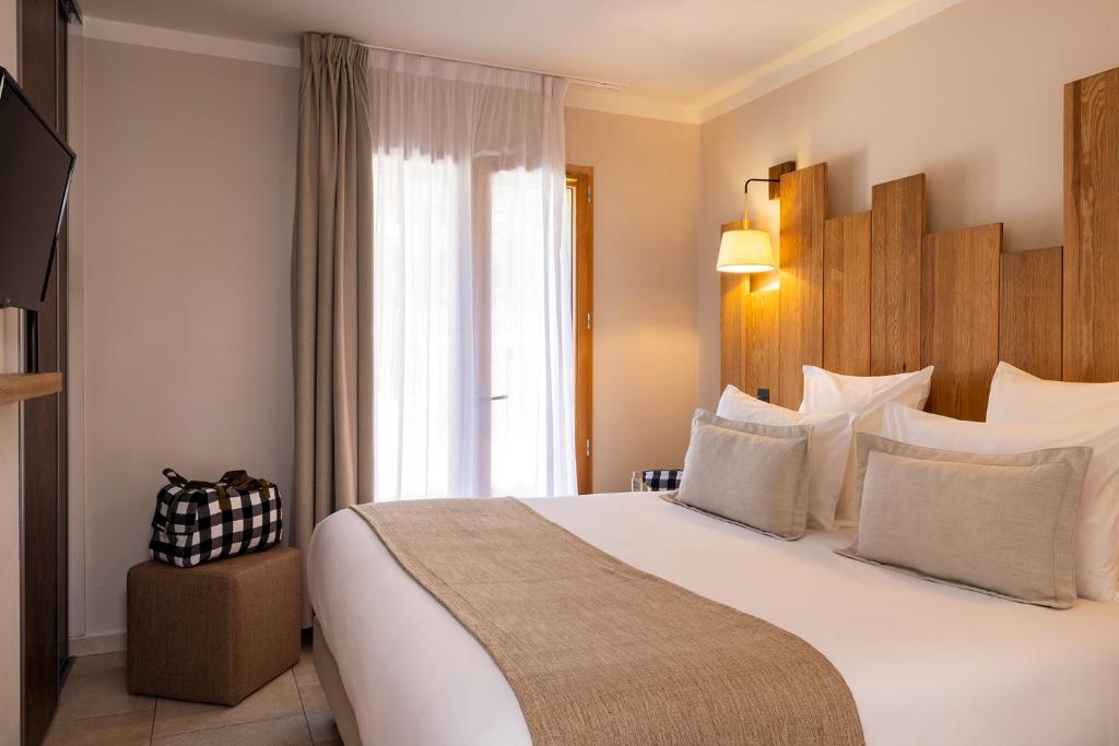 ein Hotelzimmer mit einem großen Bett und einem Fenster in der Unterkunft Domaine du Ferret Restaurant & Spa in Cap-Ferret