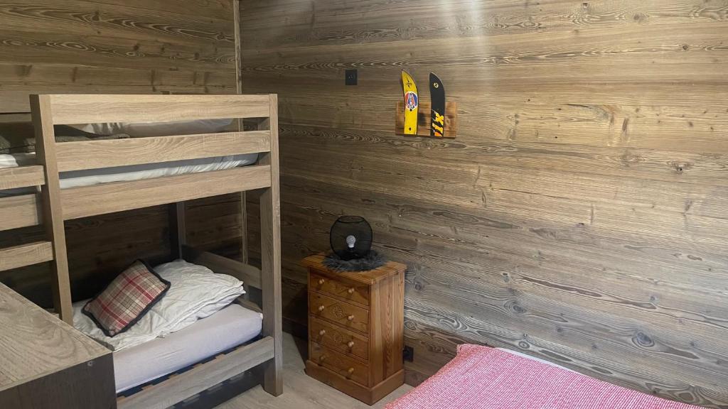 a bedroom with two bunk beds and a wooden wall at APPARTEMENT PLEIN SUD AUX SAISIES N°6 in Les Saisies