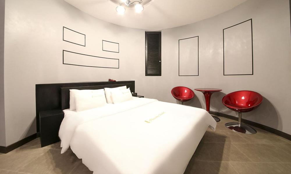 a bedroom with a white bed and two red chairs at Paju Picasso in Paju