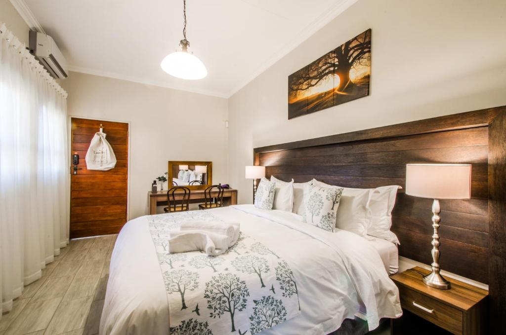 - une chambre avec un grand lit et une tête de lit en bois dans l'établissement Three Olives Guesthouse, à Centurion