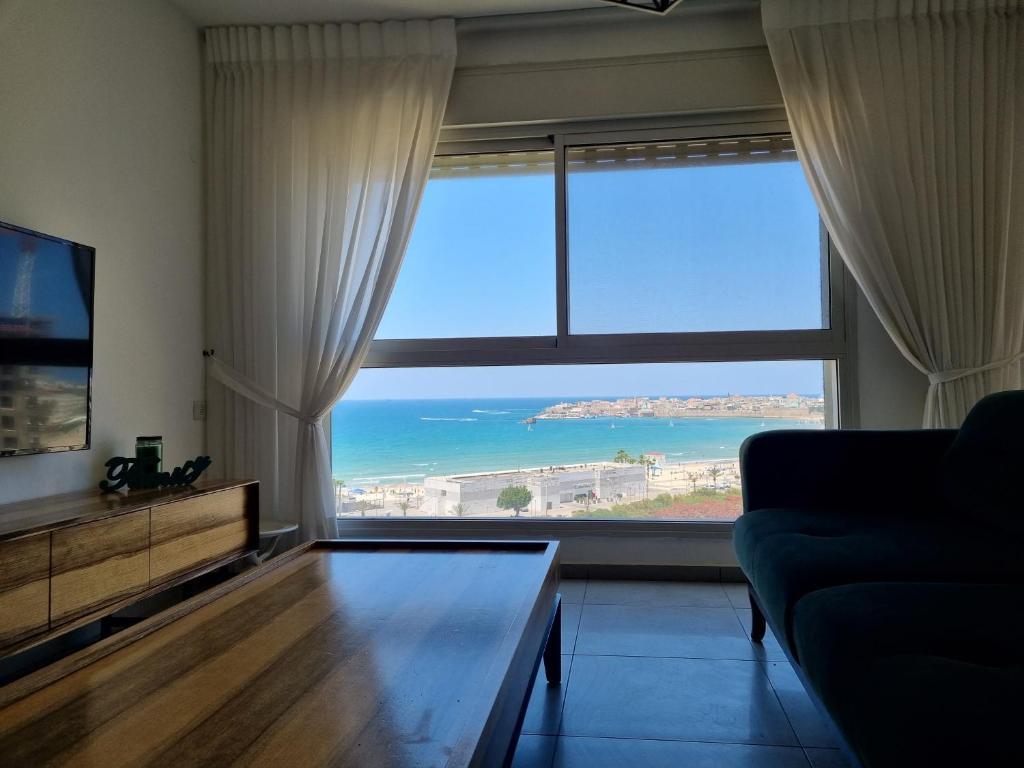 a living room with a large window with a view of the ocean at Ducks on the beach in ‘Akko