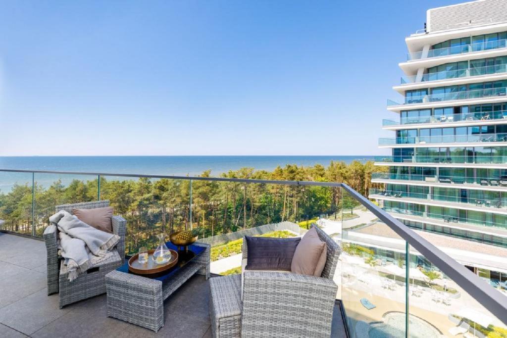a balcony with chairs and a table and a building at Cristallo Apartament Luxury Resort & SPA - Sea View by Renters Prestige in Międzyzdroje