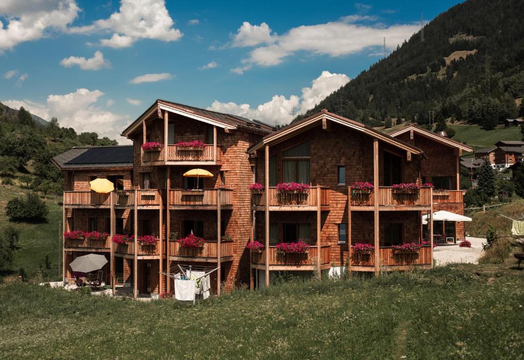 uma casa numa colina com flores nas varandas em BerglandHof Hotel Ernen em Ernen