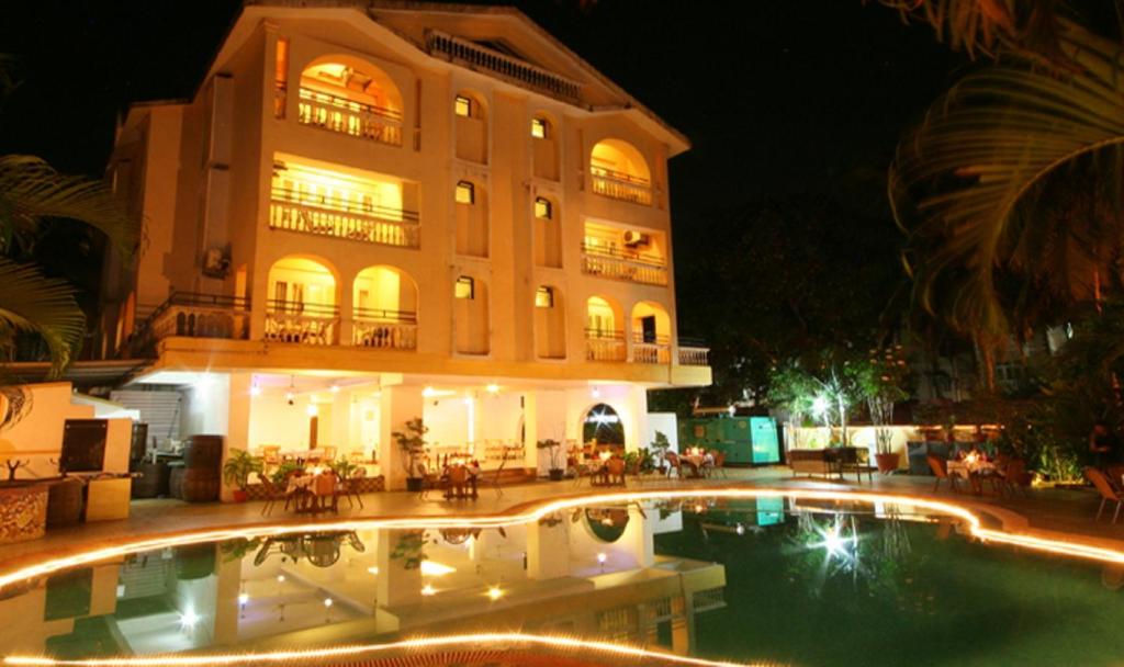 a building with a swimming pool in front of a building at Lambana Resort in Calangute