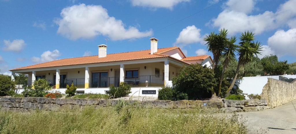 Casa blanca con techo rojo y palmera en Villa da Bica, en Lourinhã
