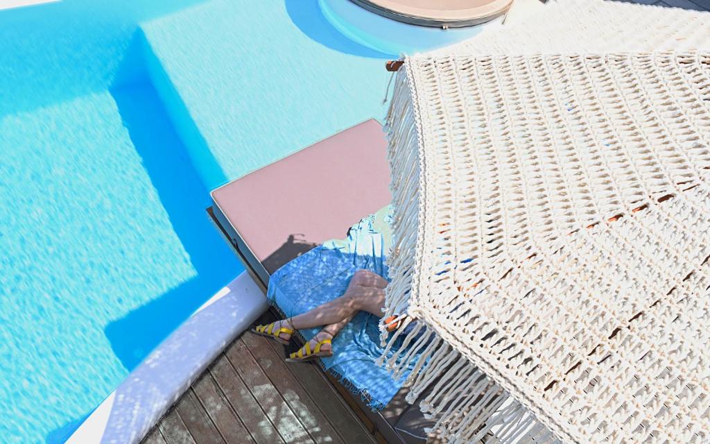 a person laying in a cage next to a swimming pool at Keablue in Melissaki