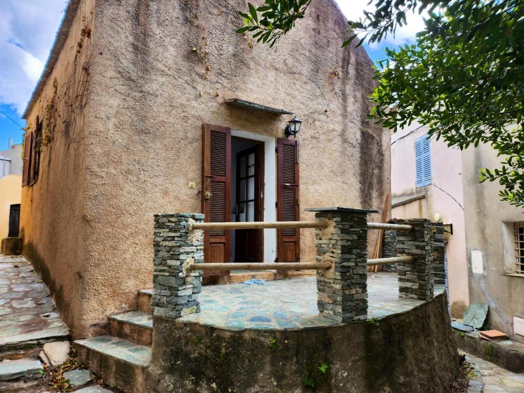 um antigo edifício de pedra com uma porta e escadas em Maison de 2 chambres avec terrasse amenagee et wifi a Rogliano em Rogliano