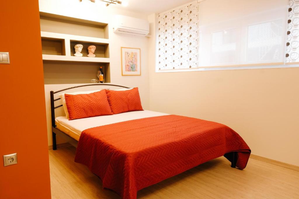 ein kleines Schlafzimmer mit einem Bett mit einer orangefarbenen Decke in der Unterkunft Venizelou Comfort & Living I in Kavala