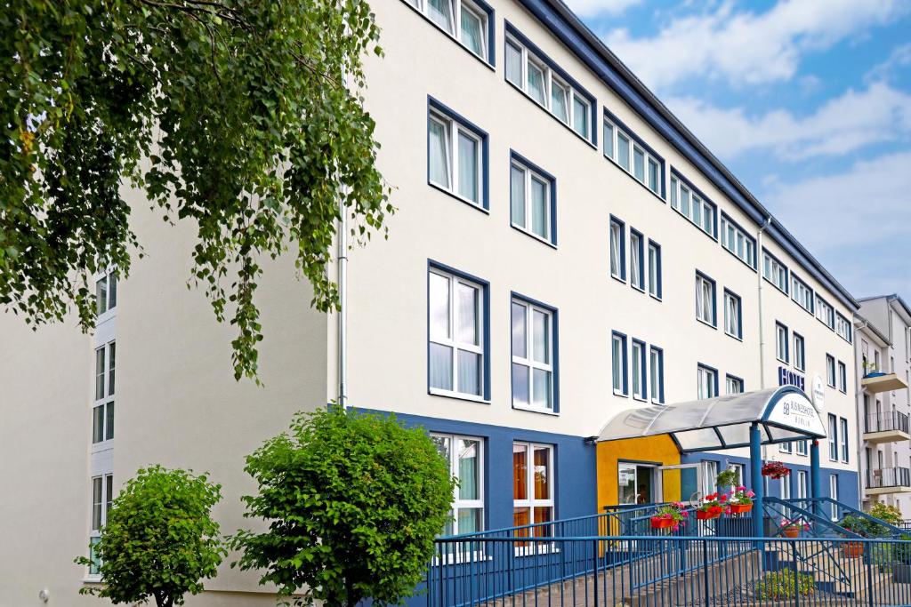 ein Apartmenthaus mit einem blauen Zaun in der Unterkunft Businesshotel Berlin in Berlin