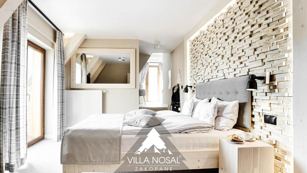 1 dormitorio con 1 cama grande y pared de ladrillo en VILLA NOSAL - Zakopane, en Zakopane