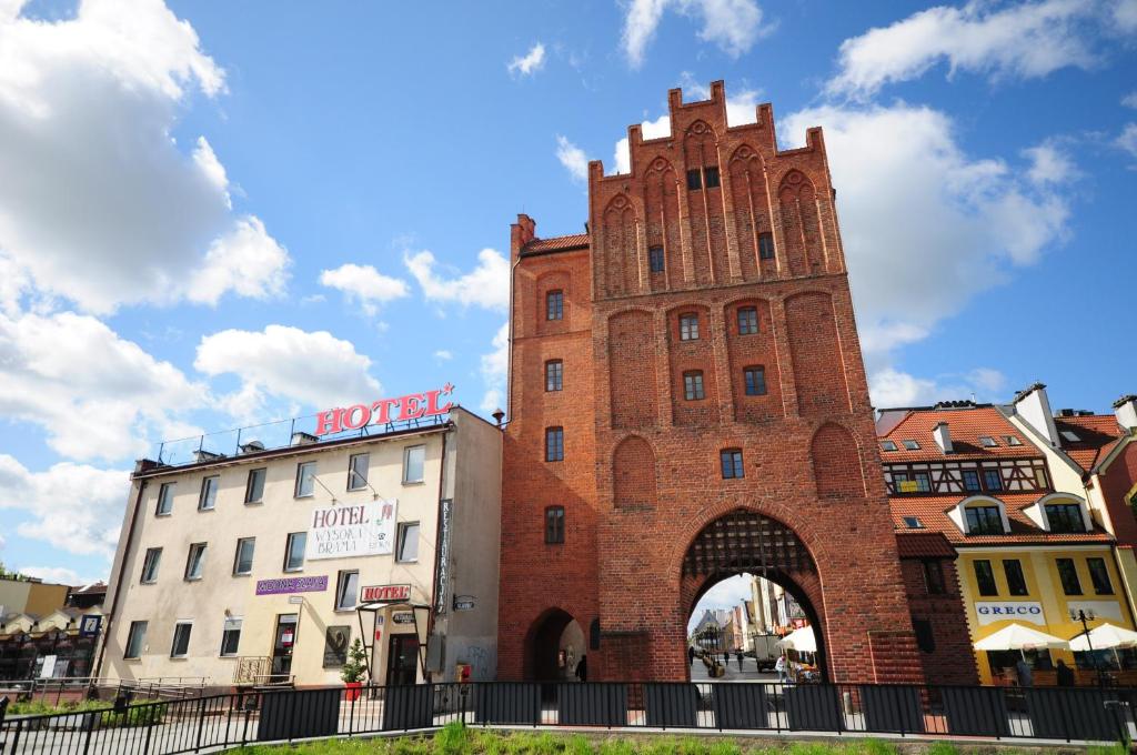 a tall brick building with an archway in a city at Hotel Wysoka Brama in Olsztyn