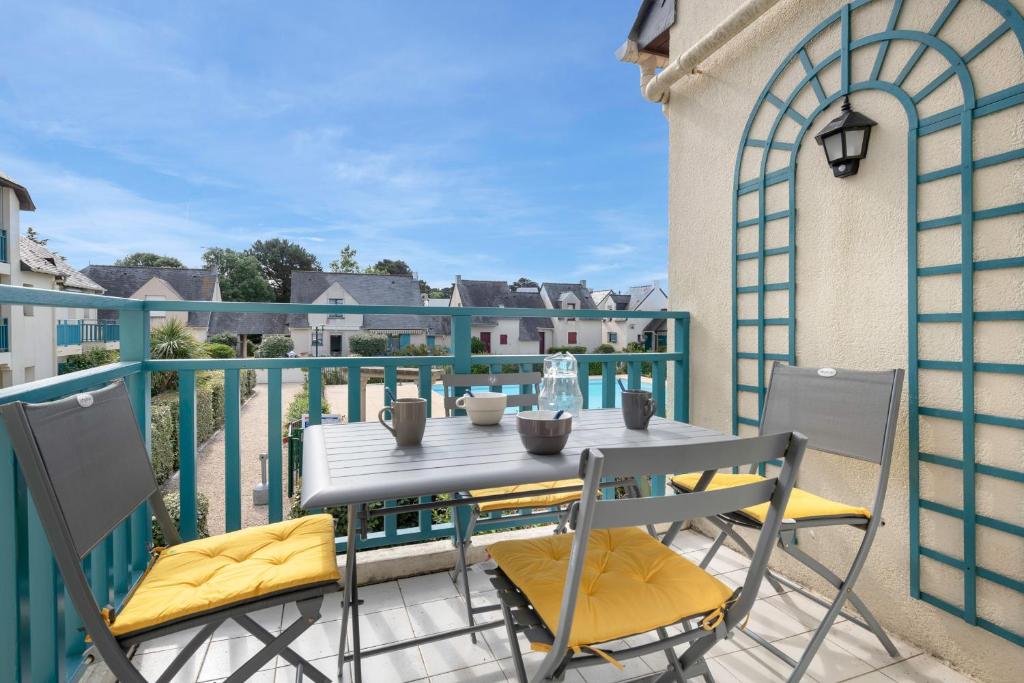 un tavolo e due sedie su un balcone di Appartement en résidence avec piscine a Batz-sur-Mer