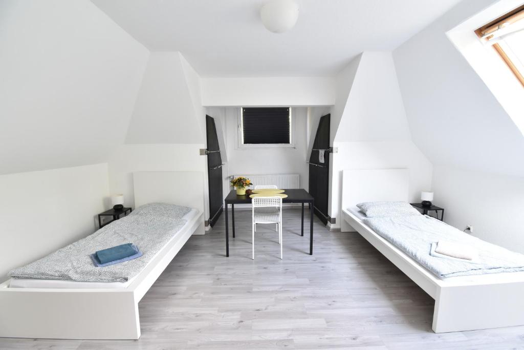 two beds in a room with a table at CoreRooms - kleines Apartment Essen Kray in Essen