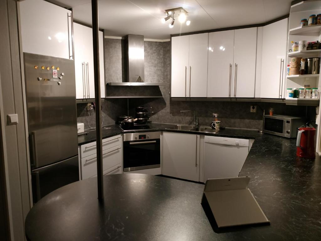 a kitchen with white cabinets and a black counter top at Apartament 2 in Havøysund