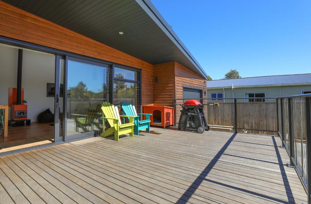 a deck with chairs and a grill on a house at Hannah's Bay Hideaway in Rotorua