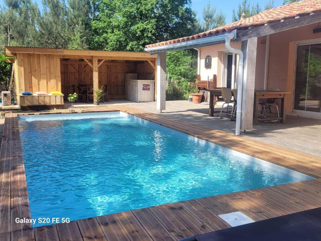 une piscine avec une terrasse et une maison dans l'établissement Grande maison de vacances 12pers PISCINE, à Béliet