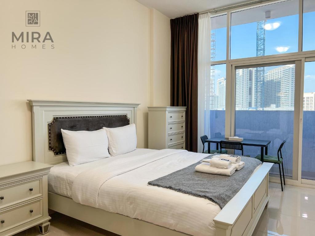 Mira Holiday Homes - Serviced apartment in Dubai Land في دبي: غرفة نوم بسرير كبير مع نافذة كبيرة