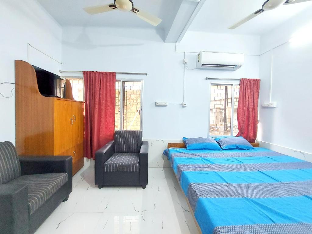 a bedroom with two beds and a chair at Chaiti Lodge - Santiniketan Bolpur in Bolpur