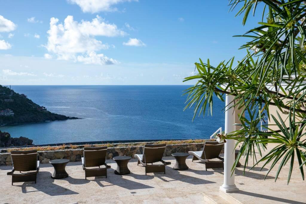 een patio met stoelen en uitzicht op de oceaan bij Maria Bluff Estate in Cruz Bay