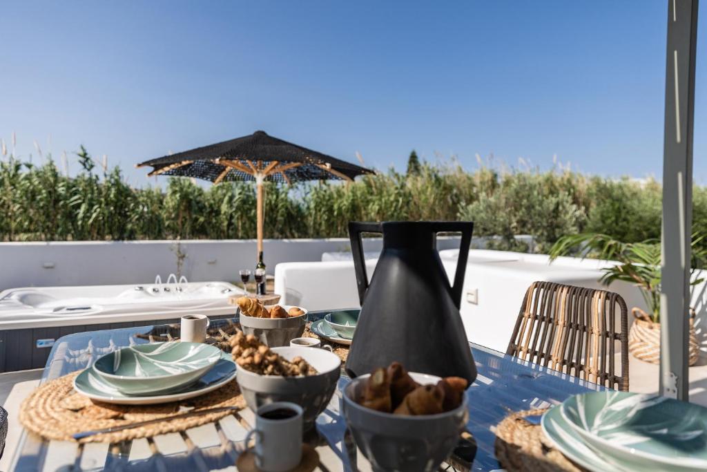 una mesa con platos y un jarrón sobre una mesa en Arsenis Luxury Villas, en Plaka