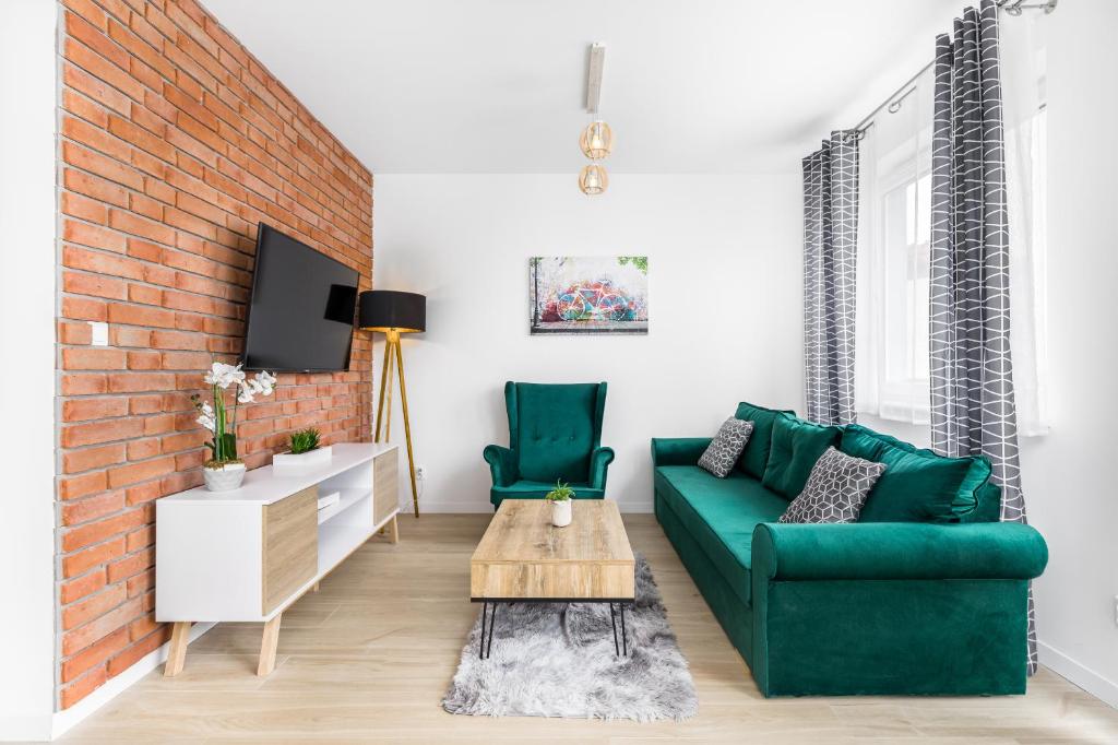 uma sala de estar com um sofá verde e uma parede de tijolos em Bm Apartamenty w Centrum Szczecin em Szczecin