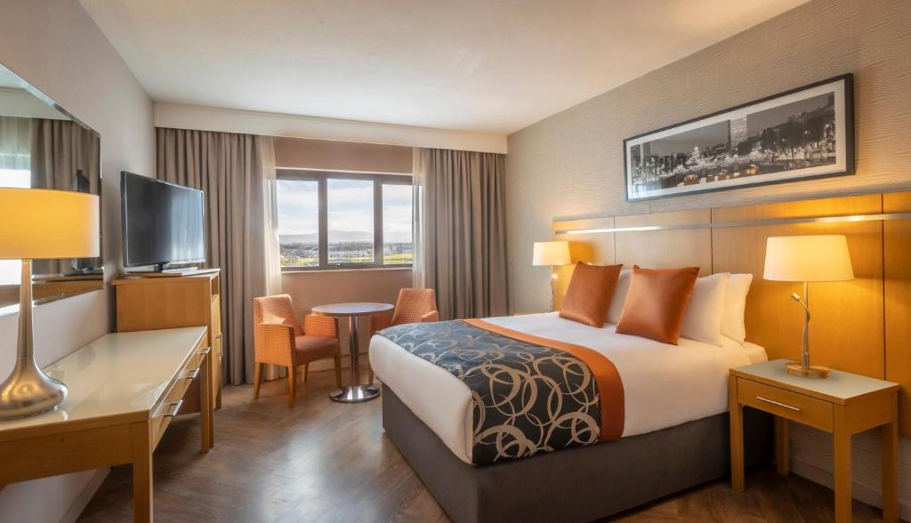 クロンドーキンにあるClayton Hotel Liffey Valleyのベッド、デスク、テレビが備わるホテルルームです。