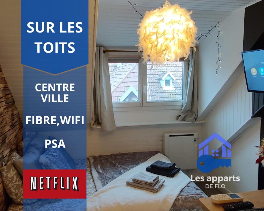 Habitación con cama y lámpara de araña. en Sur les toits, studio centre-ville, WIFI Netflix, en Montbéliard