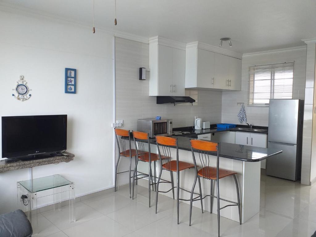 a kitchen with a bar with chairs and a refrigerator at Afsaal Sea view apartments in Amanzimtoti