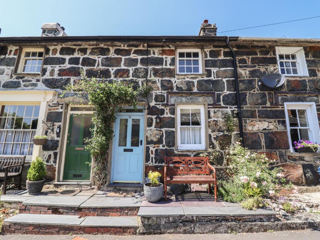 a stone house with a bench in front of it at Llygoden Cottage in Caernarfon