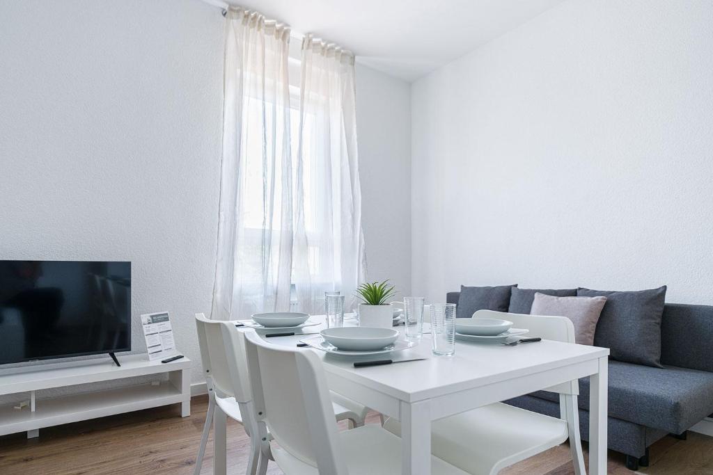 uma sala de jantar branca com uma mesa branca e uma televisão em Nice Apartment in Offenbach a. M. em Offenbach