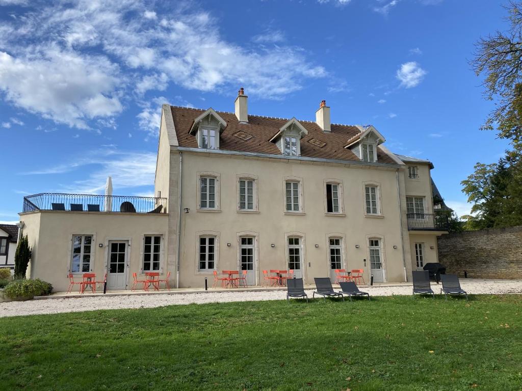 une grande maison blanche avec des chaises en face de celle-ci dans l'établissement Manoir de Villamont, à Savigny-lès-Beaune