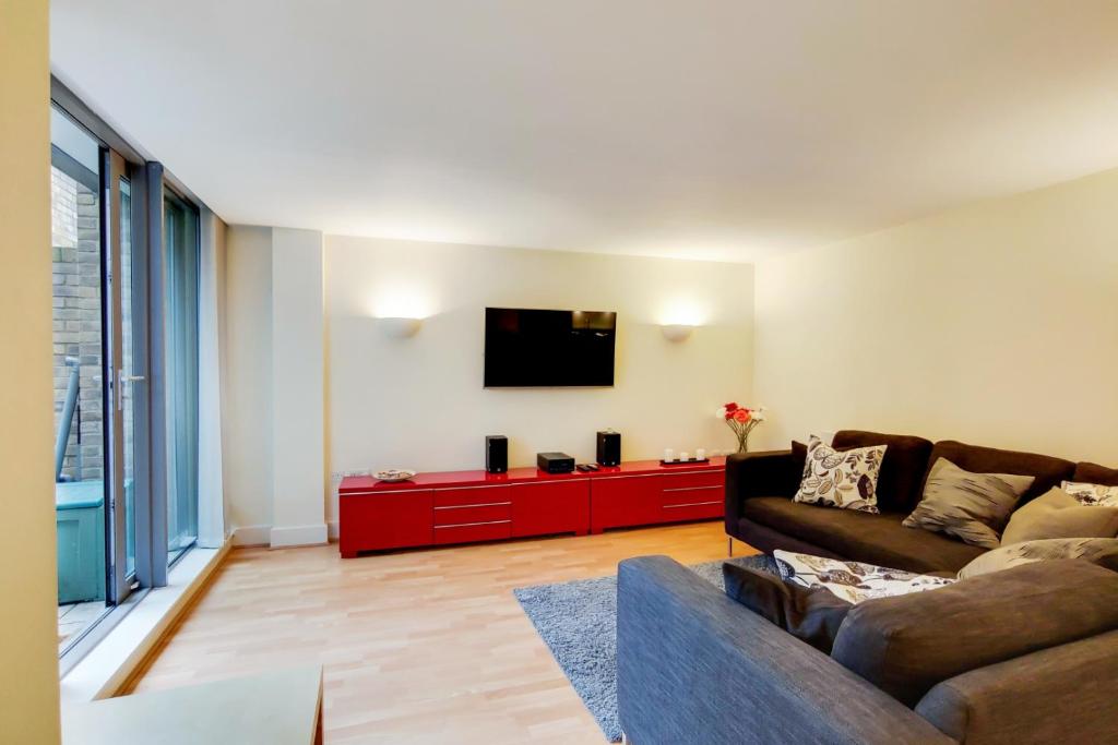 a living room with a couch and a flat screen tv at Spacious 2 bed 2 bath Kings Cross Apartment in London