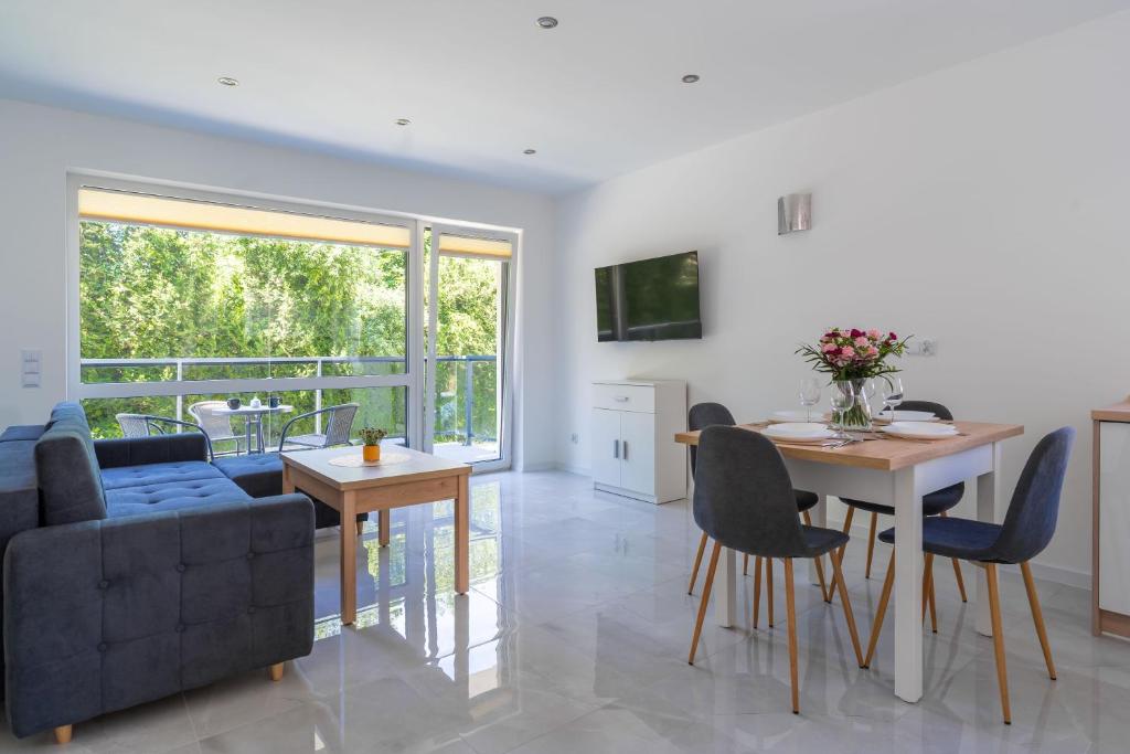 a living room with a couch and a table and chairs at Apartamenty Olchowa z tarasem w spokojnej okolicy - Dream Apart in Ustroń