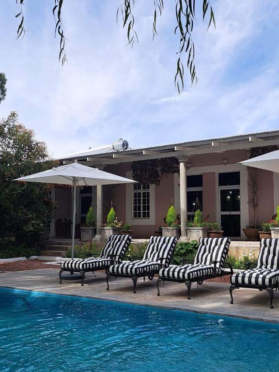 a group of lounge chairs next to a swimming pool at The Hanover Luxury Hotel in Hanover