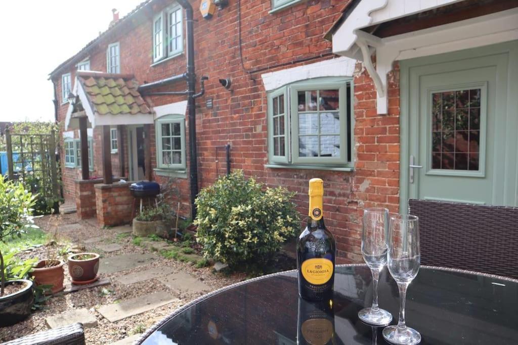 a bottle of wine sitting on a table with two glasses at Cherry Tree Cottage Close to Belvoir Castle. Sleeps 6. Dogs v welcome. in Redmile