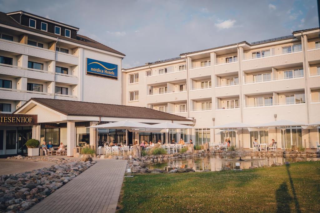 einen Blick nach außen auf ein Hotel mit Tischen und Stühlen in der Unterkunft nordica Hotel Friesenhof in Büsum