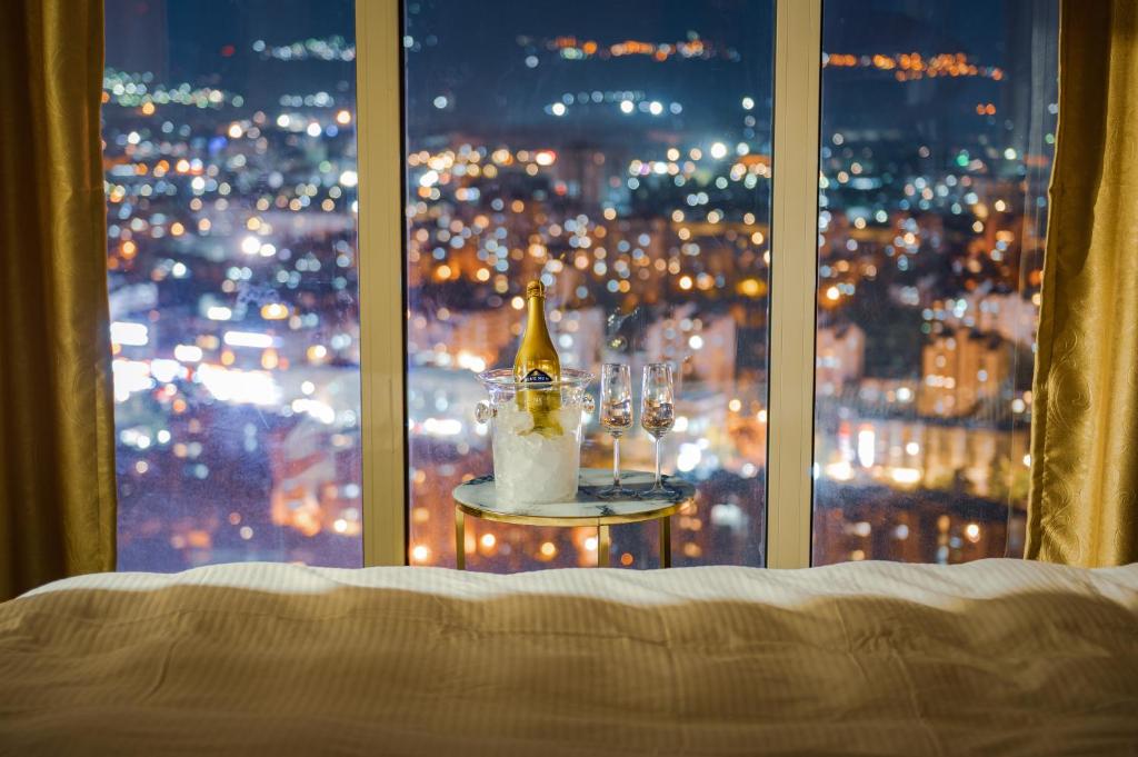 a bed with a view of a city from a window at Sky Deluxe 3 Fitness & Spa in Skopje