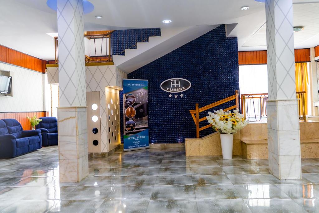 a lobby with a staircase and a blue brick wall at Hotel Turist in Pucioasa