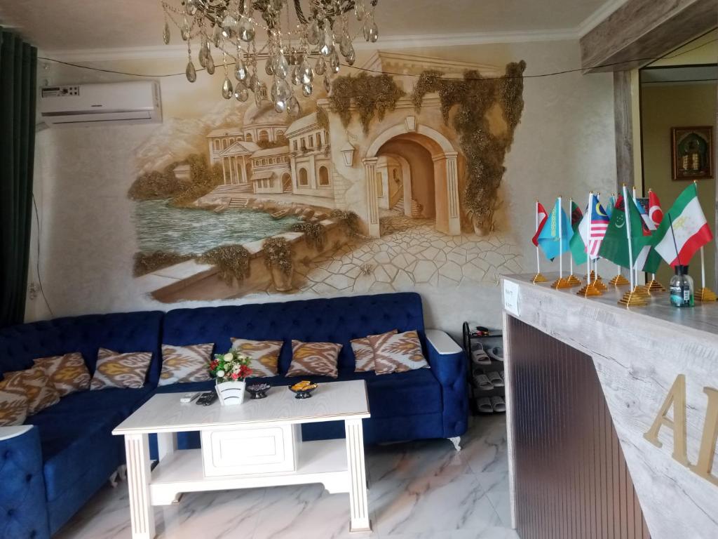 sala de estar con sofá azul y mural en Hotel Al Hayit Teracce, en Bukhara
