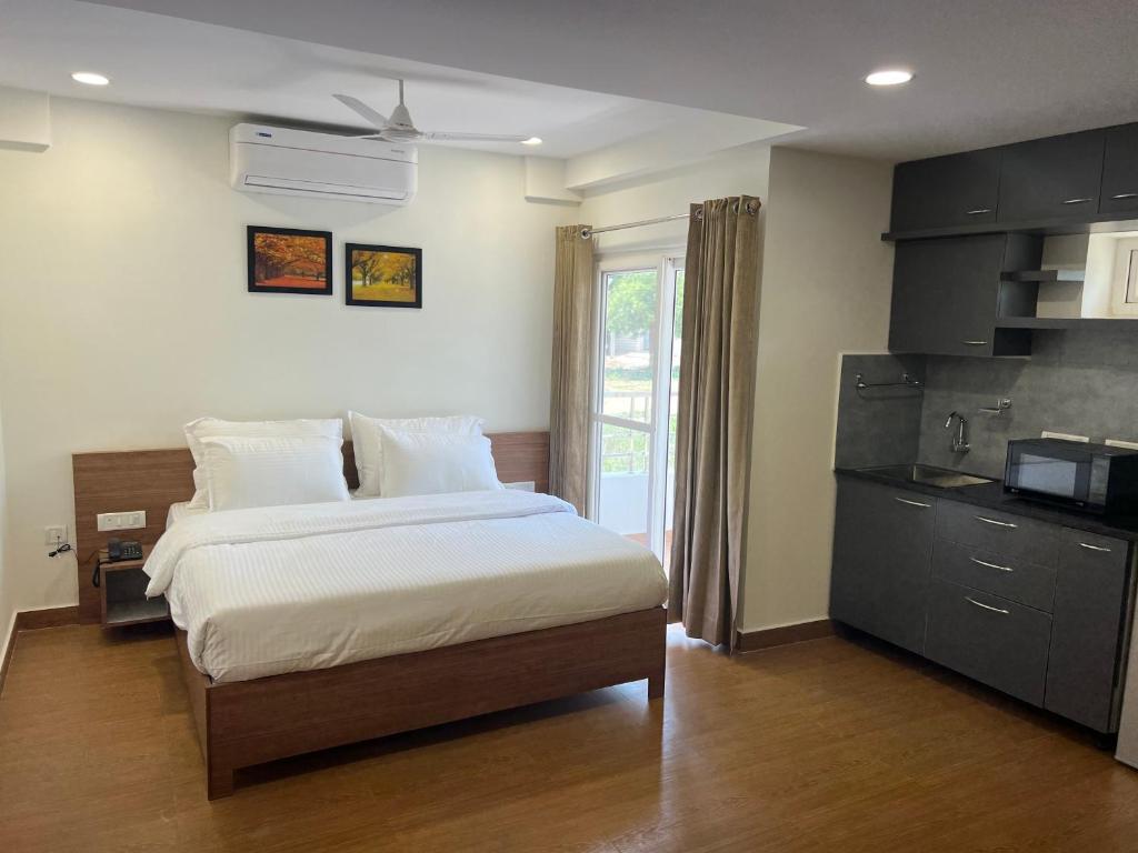 a bedroom with a large bed and a kitchen at Palladium Luxury Suites Financial District Unit I in Hyderabad