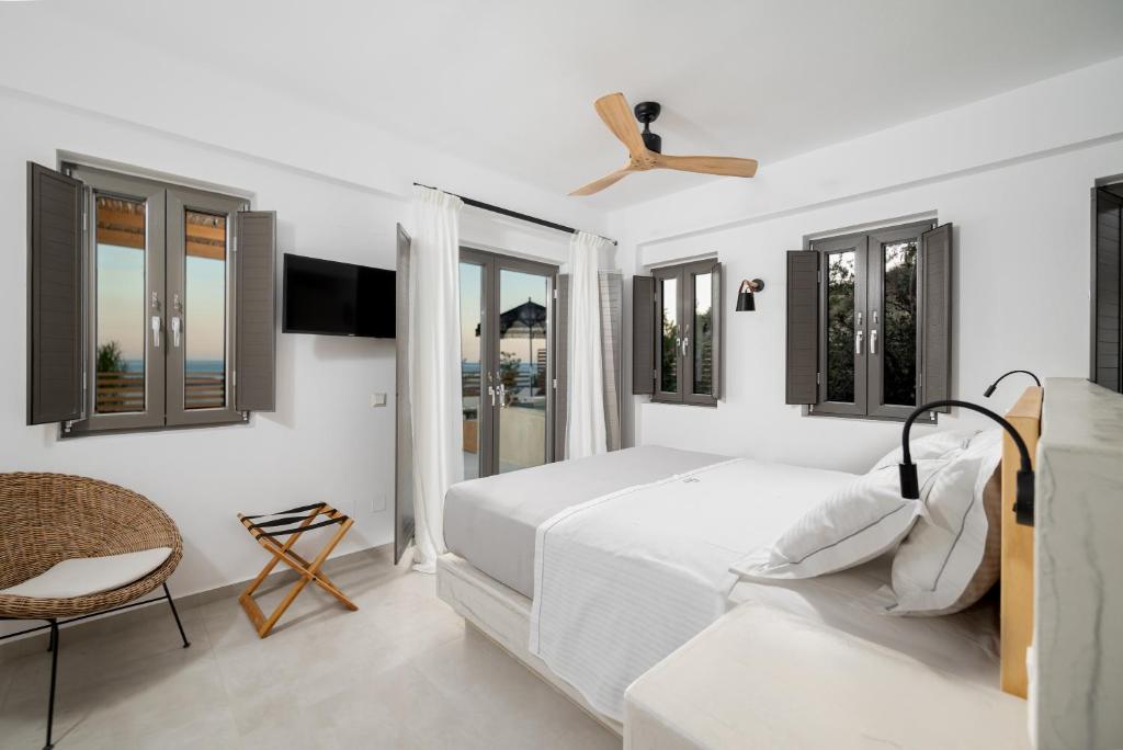a white bedroom with a bed and windows at Mnḗmē Suites & Villas in Kastrí