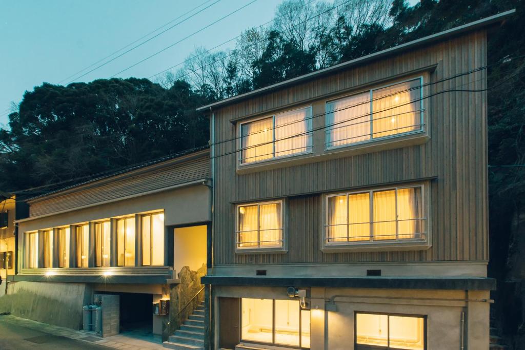una casa con ventanas iluminadas en un lateral en 宿 ロイノハコ en Gotsu
