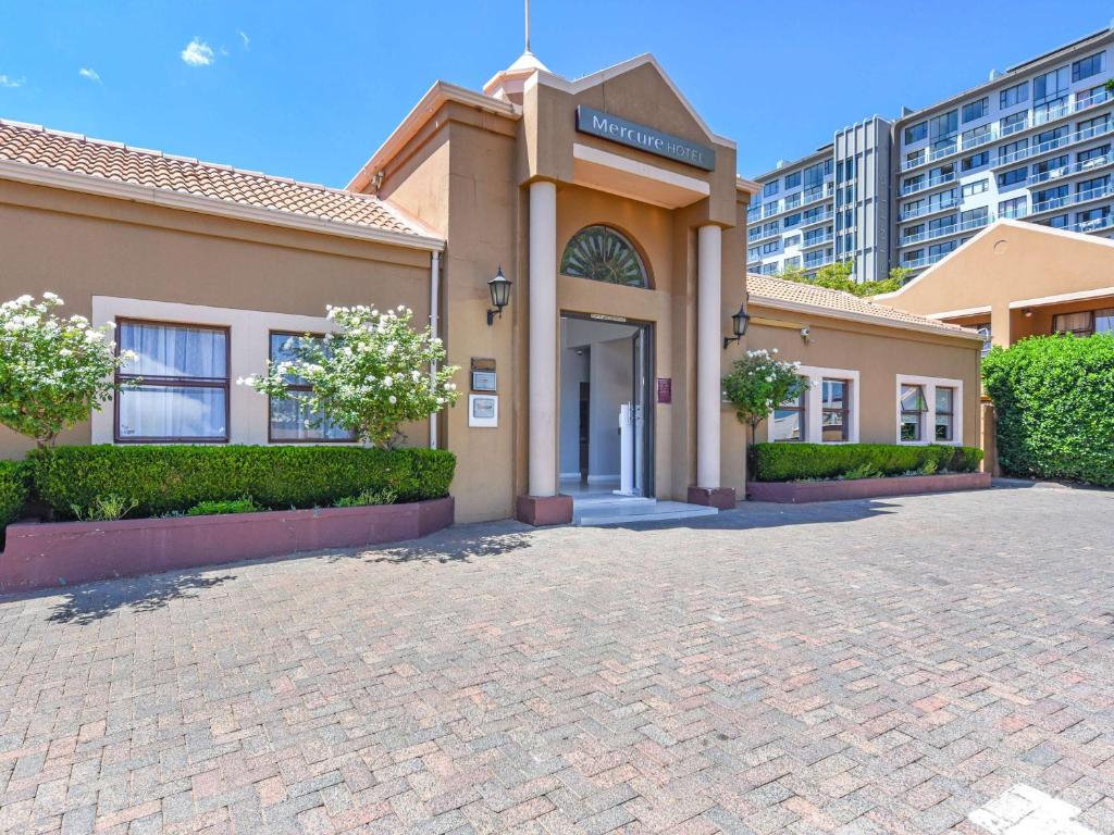 une maison avec une allée en briques en face d'un bâtiment dans l'établissement Mercure Hotel Bedfordview, à Johannesbourg