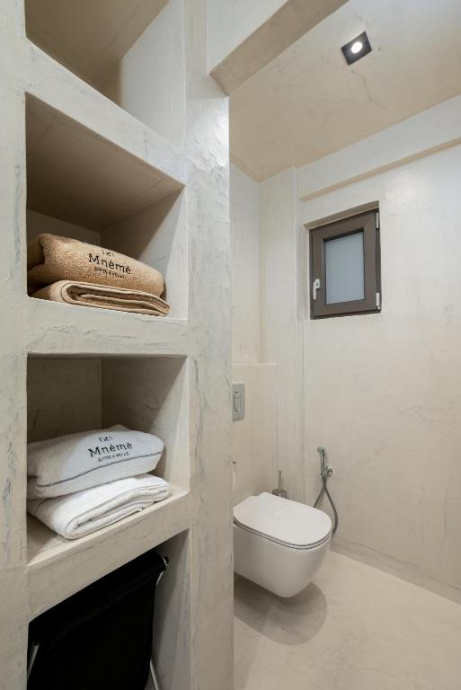 a white bathroom with a white toilet and towels at Mnḗmē Suites & Villas in Kastrí