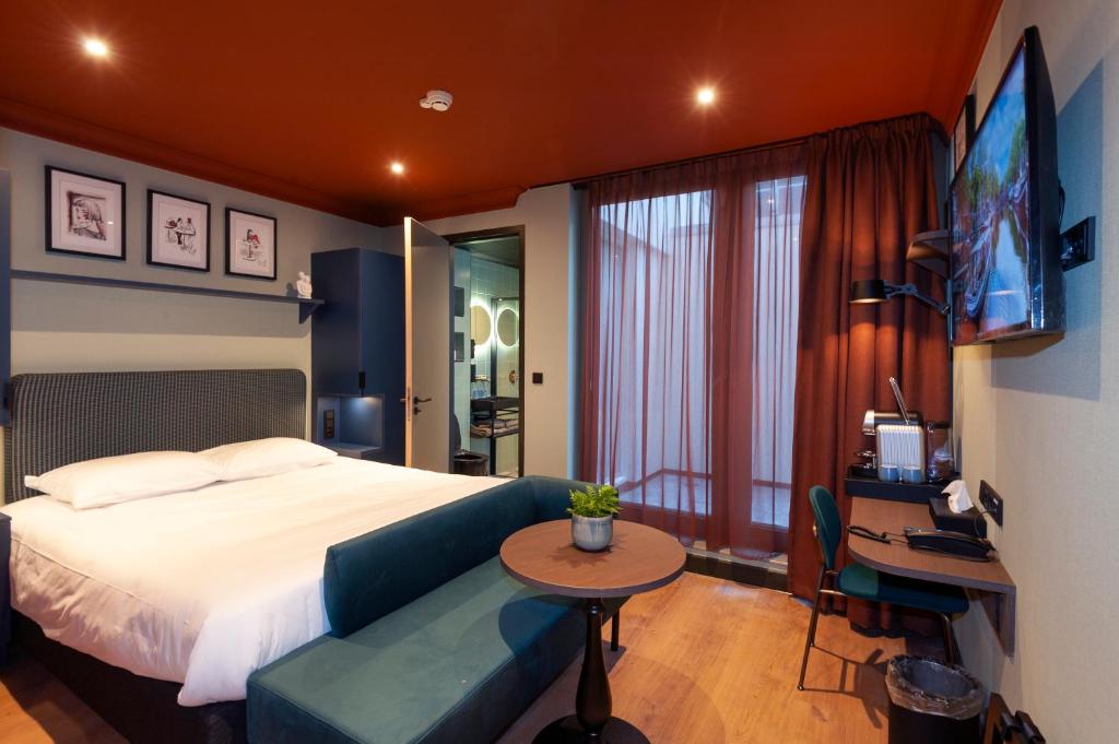 a bedroom with a bed and a table and a television at Hotel Nicolaas Witsen in Amsterdam