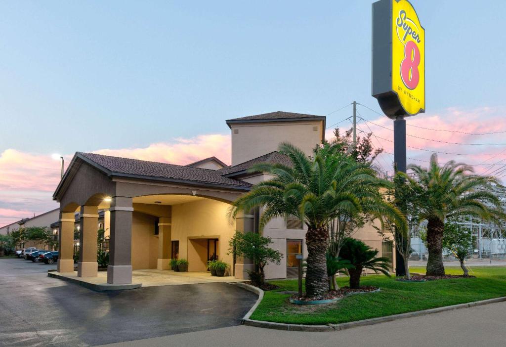 un hôtel avec des palmiers devant un bâtiment dans l'établissement Super 8 by Wyndham Diberville Biloxi Area, à Biloxi