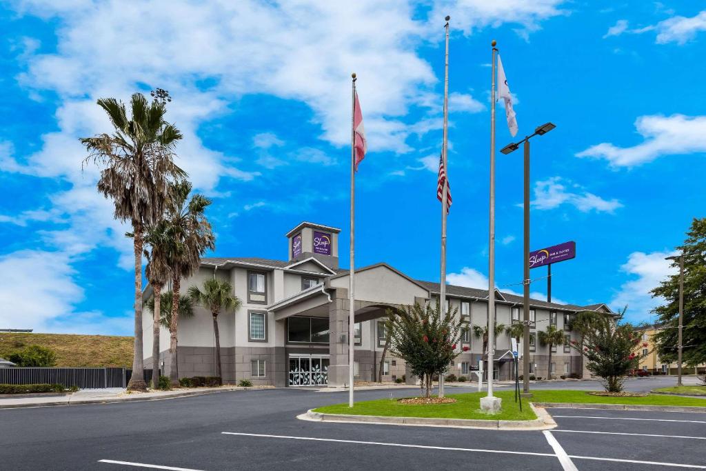 a building with two flags in a parking lot at Sleep Inn & Suites in Valdosta