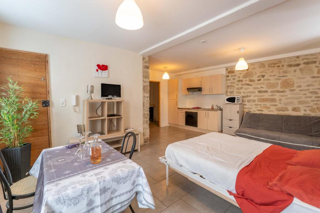 a bedroom with a bed and a table and a couch at Studio Meuble Pied Du Ventoux in Malaucène