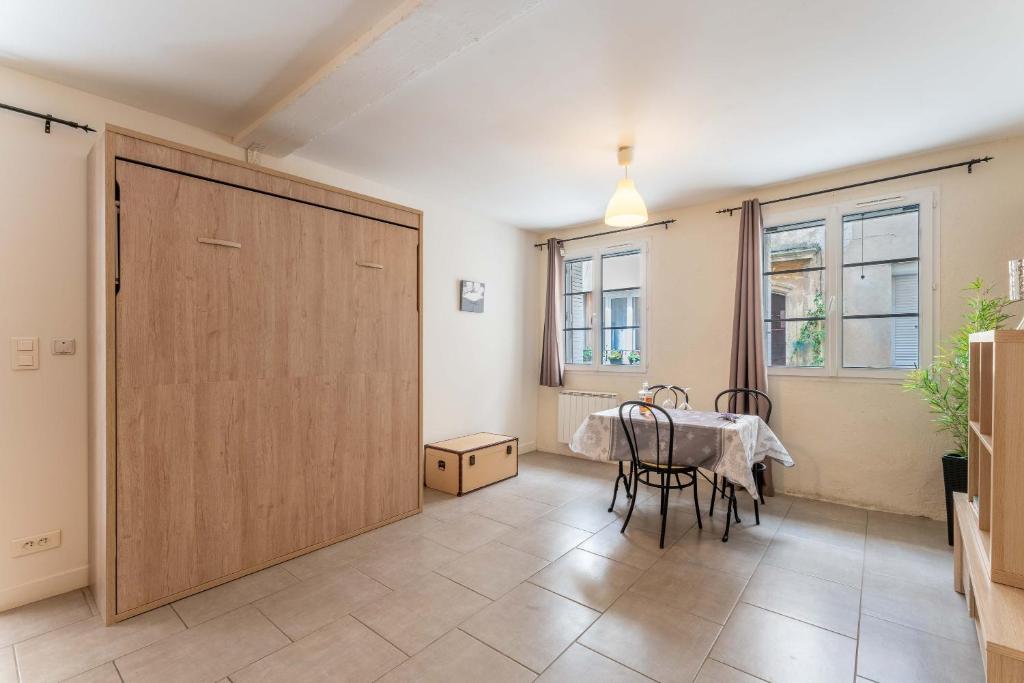 a dining room with a table and a large wooden door at Studio Meuble Pied Du Ventoux in Malaucène