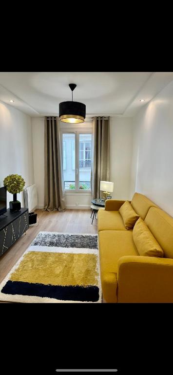 - un salon avec un canapé jaune et une fenêtre dans l'établissement Charming parisian apartment, à Paris